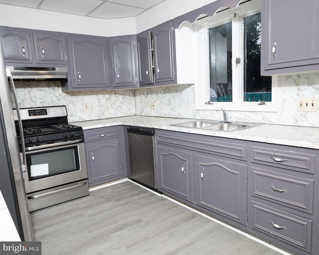 kitchen featuring stainless steel appliances, light hardwood / wood-style floors, sink, gray cabinets, and tasteful backsplash