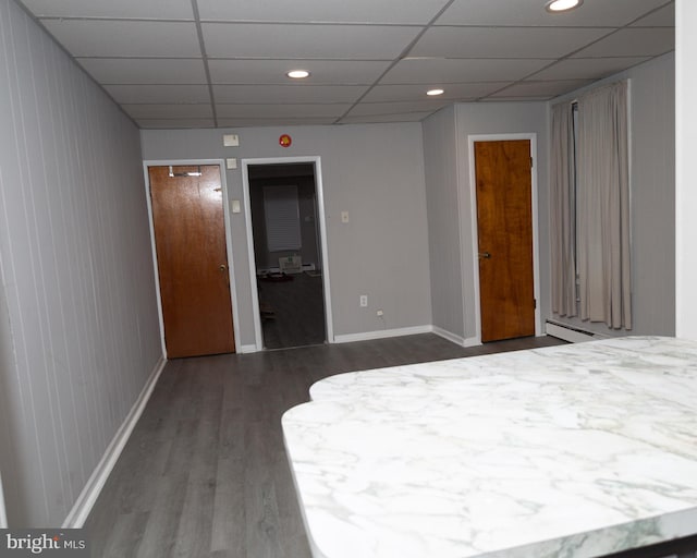 unfurnished bedroom with dark wood-type flooring and a drop ceiling