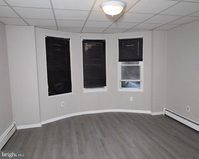 unfurnished room with baseboard heating, hardwood / wood-style flooring, and a drop ceiling