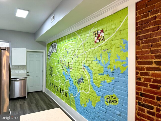 kitchen featuring visible vents, brick wall, dark wood finished floors, white cabinets, and stainless steel appliances