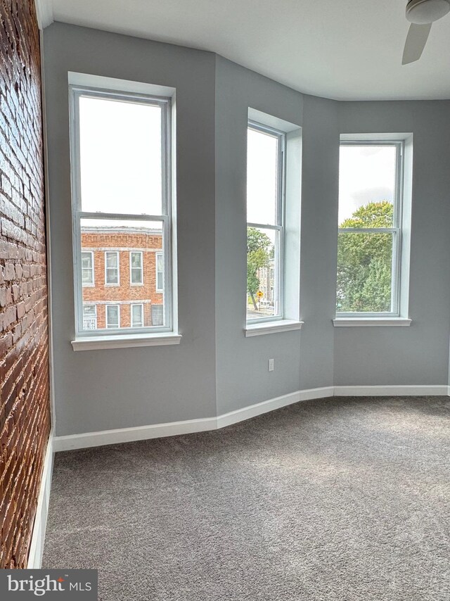 carpeted spare room featuring baseboards and ceiling fan