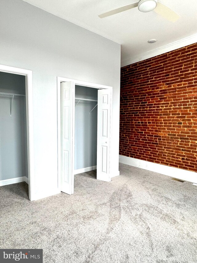 unfurnished bedroom featuring brick wall, ceiling fan, and carpet floors