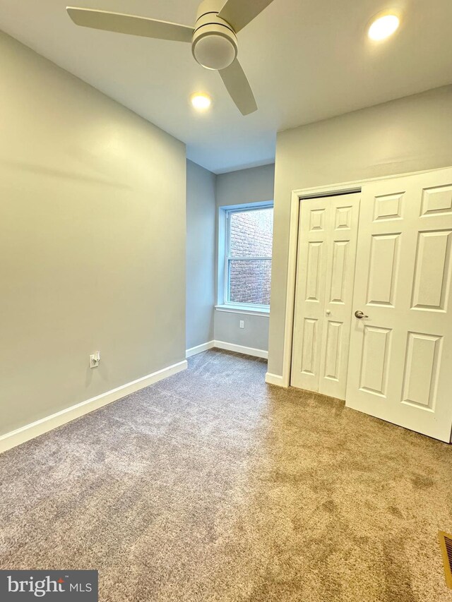 unfurnished bedroom featuring visible vents, baseboards, carpet flooring, a closet, and a ceiling fan