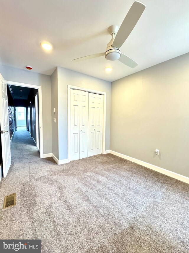 unfurnished bedroom featuring visible vents, a closet, carpet, baseboards, and ceiling fan