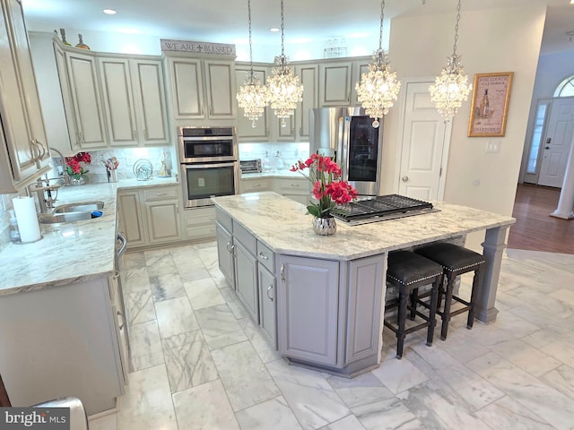 kitchen with sink, stainless steel appliances, light stone counters, tasteful backsplash, and a kitchen island