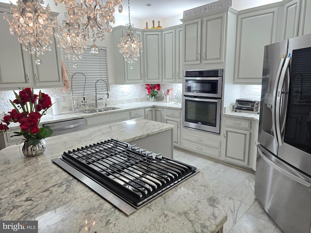 kitchen with hanging light fixtures, appliances with stainless steel finishes, sink, and decorative backsplash