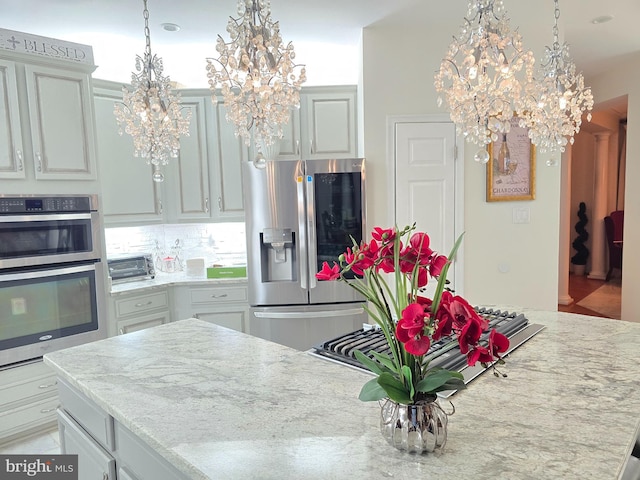 kitchen featuring appliances with stainless steel finishes, a notable chandelier, backsplash, and decorative light fixtures