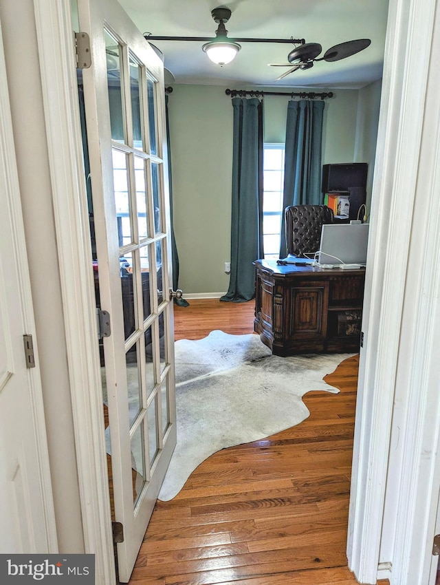 office with french doors, ceiling fan, and light wood-type flooring