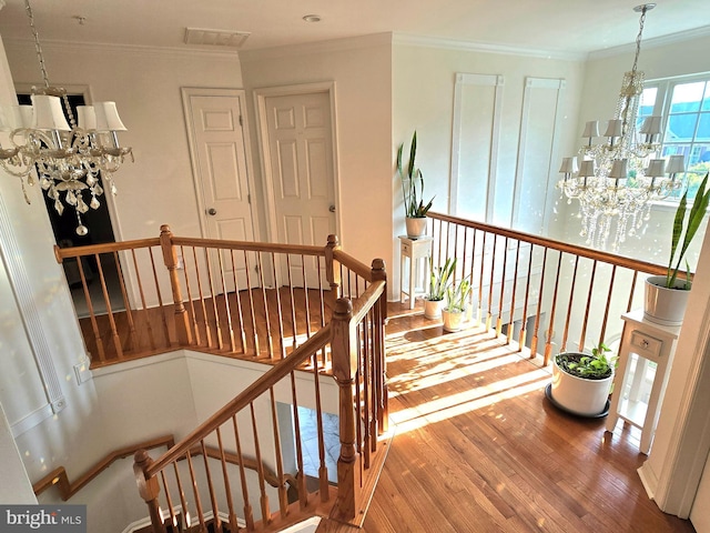 stairway featuring hardwood / wood-style floors, crown molding, and a chandelier