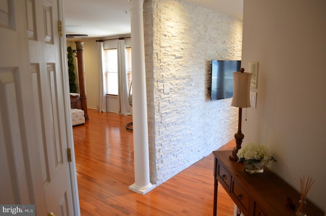 hall with decorative columns and light wood-type flooring