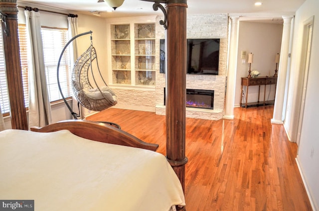 bedroom with a fireplace, wood-type flooring, and ornate columns