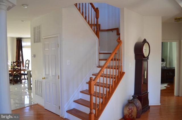 stairs with hardwood / wood-style flooring and ornate columns