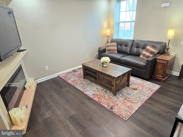 living area featuring dark wood-style floors, a fireplace, and baseboards
