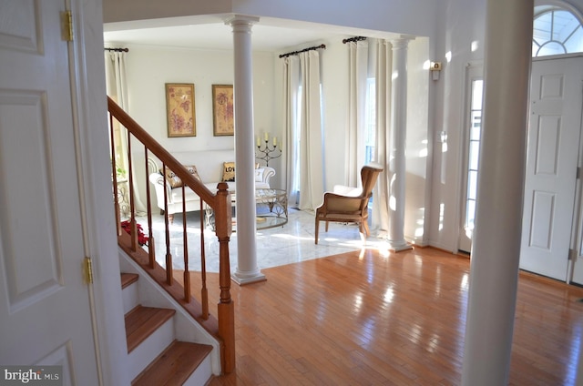 foyer featuring decorative columns, crown molding, and light wood-type flooring