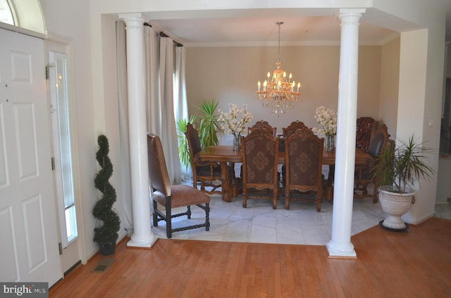 dining area with a notable chandelier, light hardwood / wood-style flooring, and ornate columns