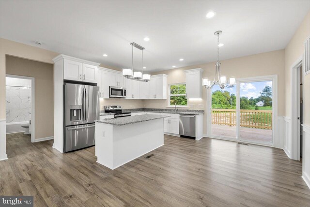 kitchen featuring stainless steel appliances, white cabinetry, a center island, and light wood-type flooring