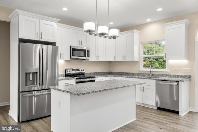 kitchen featuring stone counters, wood-type flooring, a kitchen island, stainless steel appliances, and pendant lighting