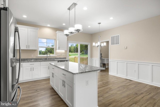 kitchen with light hardwood / wood-style floors, sink, pendant lighting, stainless steel fridge with ice dispenser, and a kitchen island