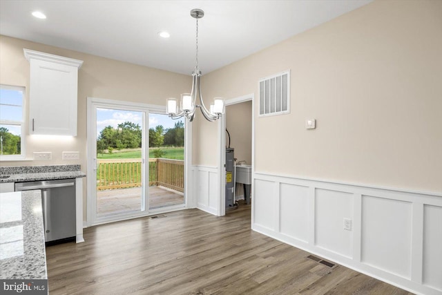 unfurnished dining area with a wealth of natural light, a notable chandelier, and wood-type flooring