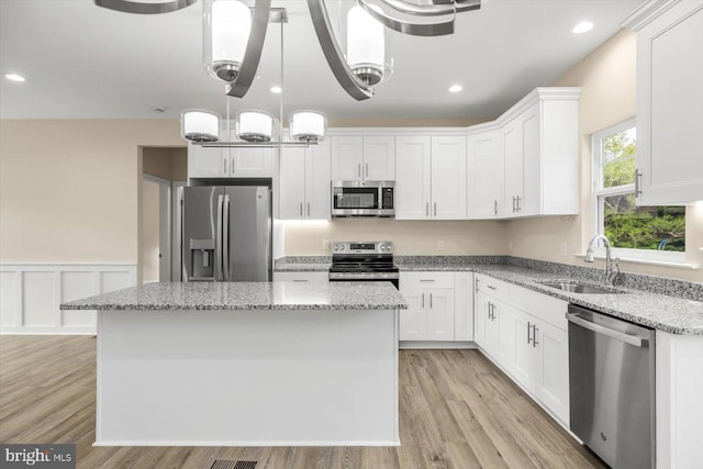 kitchen with stainless steel appliances, white cabinetry, and hardwood / wood-style flooring