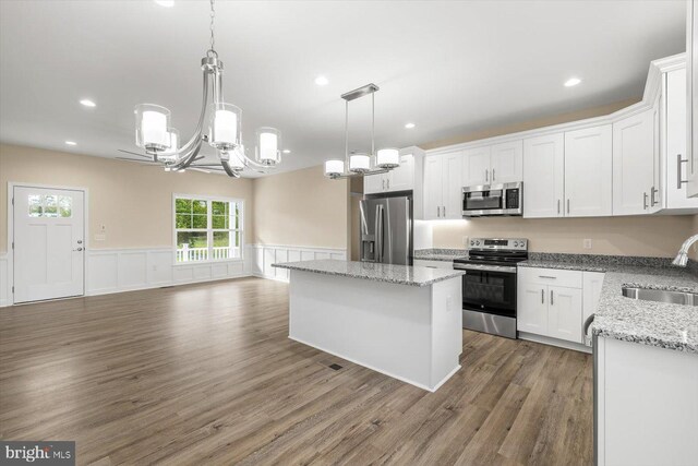 kitchen with stainless steel appliances, light hardwood / wood-style flooring, sink, light stone countertops, and white cabinets