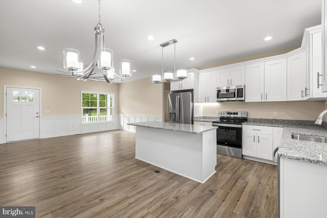 kitchen featuring stainless steel appliances, a center island, white cabinets, and a sink