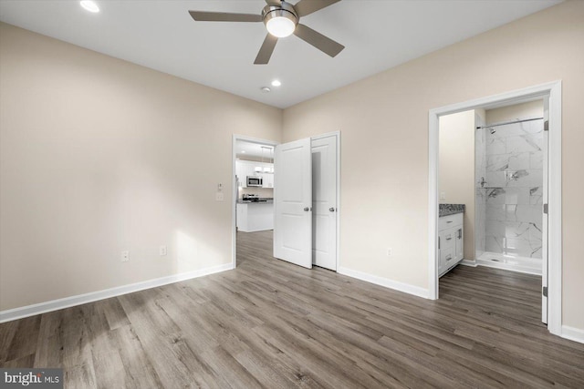 unfurnished bedroom featuring ceiling fan, ensuite bathroom, and hardwood / wood-style floors