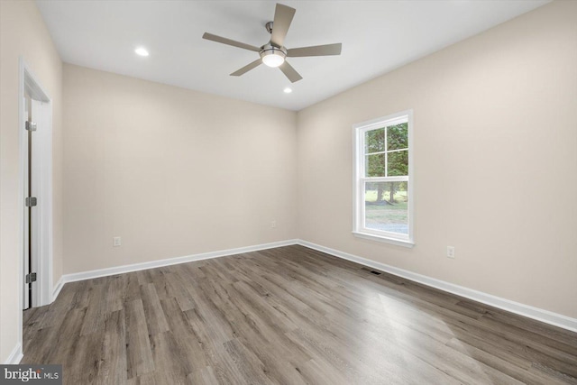 empty room featuring wood finished floors, visible vents, and baseboards