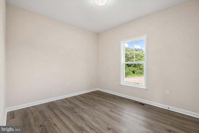 spare room featuring wood finished floors, visible vents, and baseboards