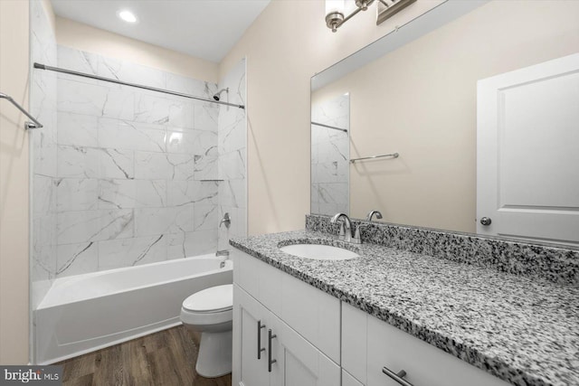 bathroom with toilet,  shower combination, wood finished floors, and vanity