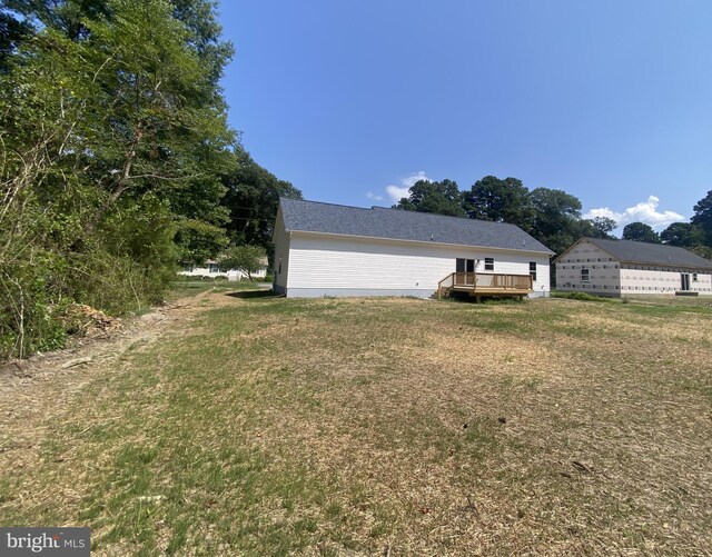 back of property with a wooden deck, central AC, and a yard