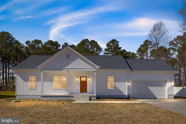 modern farmhouse style home featuring an attached garage, covered porch, roof with shingles, and gravel driveway