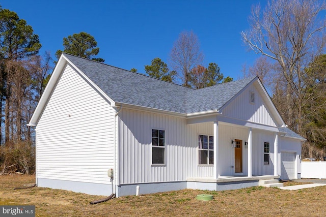 view of front of house with a garage, a shingled roof, a front lawn, and a porch