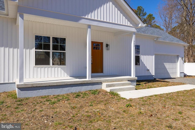 view of exterior entry featuring a garage, a porch, board and batten siding, and roof with shingles