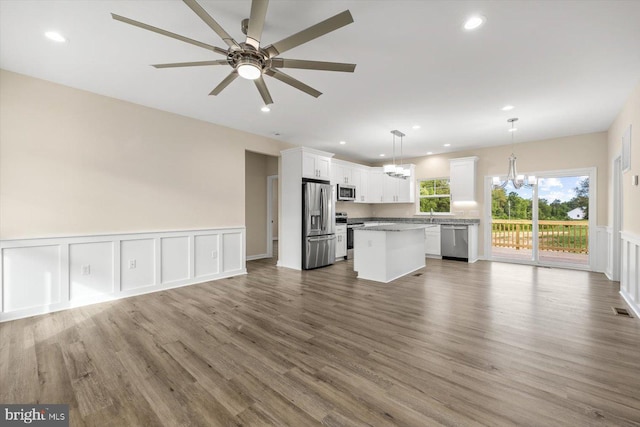 kitchen featuring a center island, appliances with stainless steel finishes, open floor plan, white cabinetry, and ceiling fan with notable chandelier