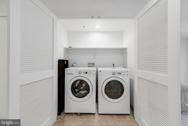 clothes washing area with washer and clothes dryer and light tile patterned floors