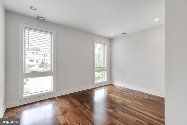 spare room featuring a wealth of natural light and dark hardwood / wood-style flooring