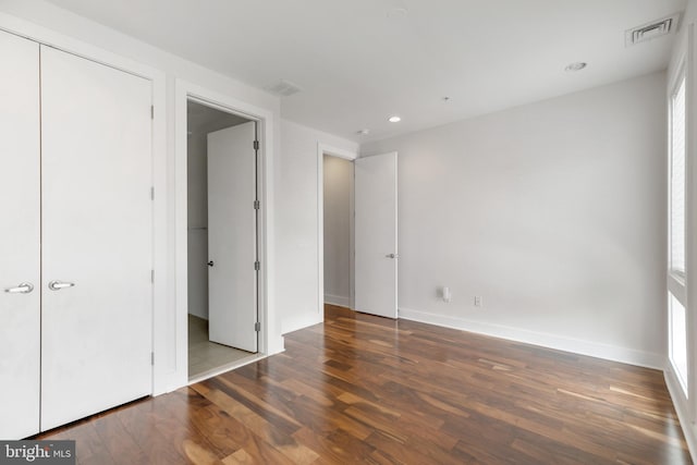 unfurnished bedroom with multiple windows, dark hardwood / wood-style floors, and a closet