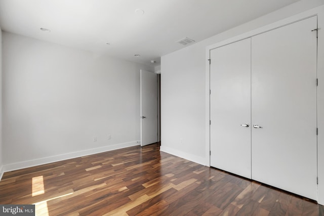 unfurnished bedroom featuring dark hardwood / wood-style floors and a closet