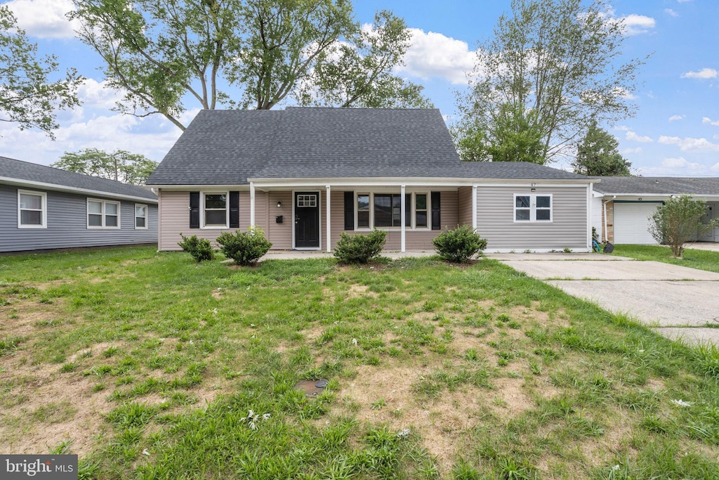 view of front of house featuring covered porch, roof with shingles, concrete driveway, and a front yard