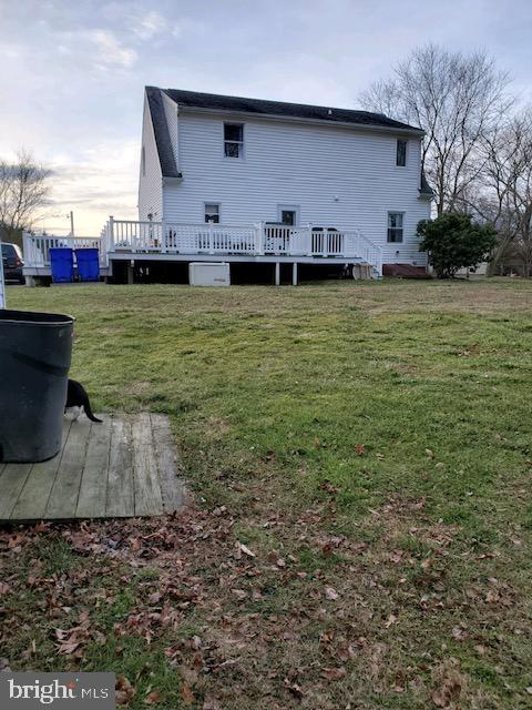 back house at dusk with a yard and a deck