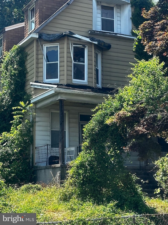 view of side of home featuring covered porch