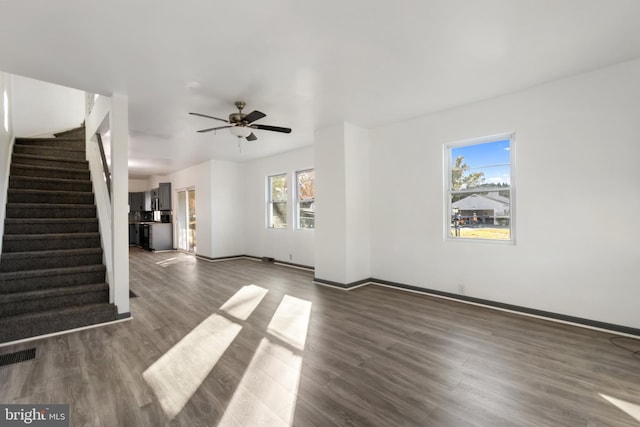 unfurnished living room featuring dark wood-type flooring and ceiling fan