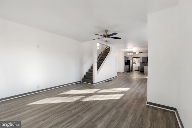 unfurnished living room with dark hardwood / wood-style flooring and ceiling fan with notable chandelier