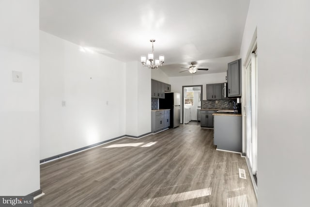 kitchen with gray cabinetry, decorative backsplash, stainless steel refrigerator, and wood-type flooring