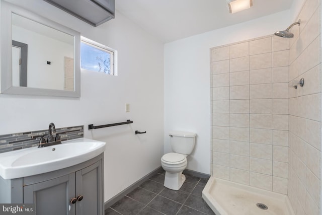 bathroom with tile patterned floors, toilet, a tile shower, and tasteful backsplash