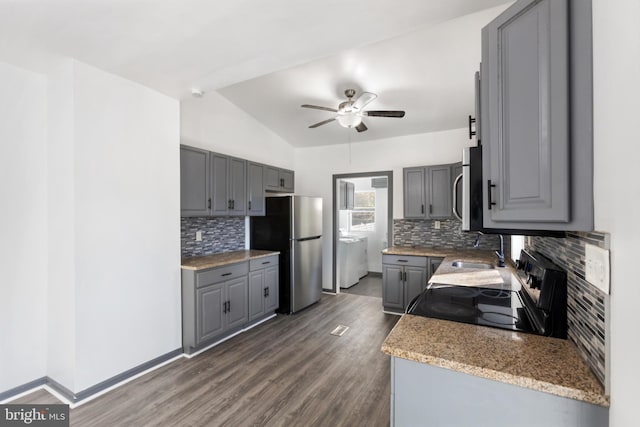 kitchen featuring decorative backsplash, appliances with stainless steel finishes, dark wood-type flooring, gray cabinetry, and vaulted ceiling