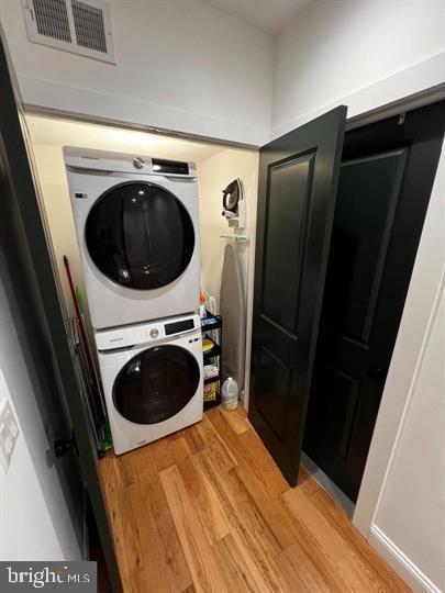 laundry room featuring stacked washer and clothes dryer and light hardwood / wood-style floors