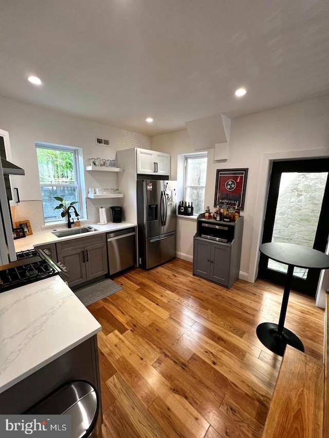 kitchen featuring appliances with stainless steel finishes, sink, light wood-type flooring, and gray cabinetry