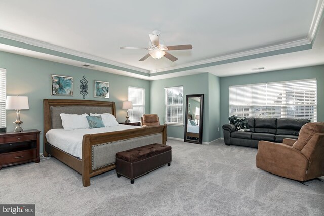 bedroom with ceiling fan, a raised ceiling, multiple windows, and light colored carpet